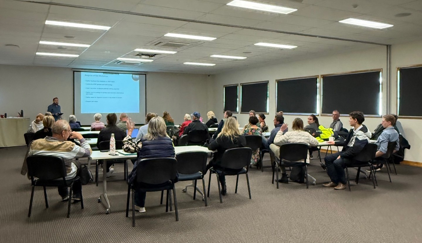 Image of a workshop in progress, with people at multiple tables viewing a presentation on a screen. Taken at the Pittsworth Function Centre. 